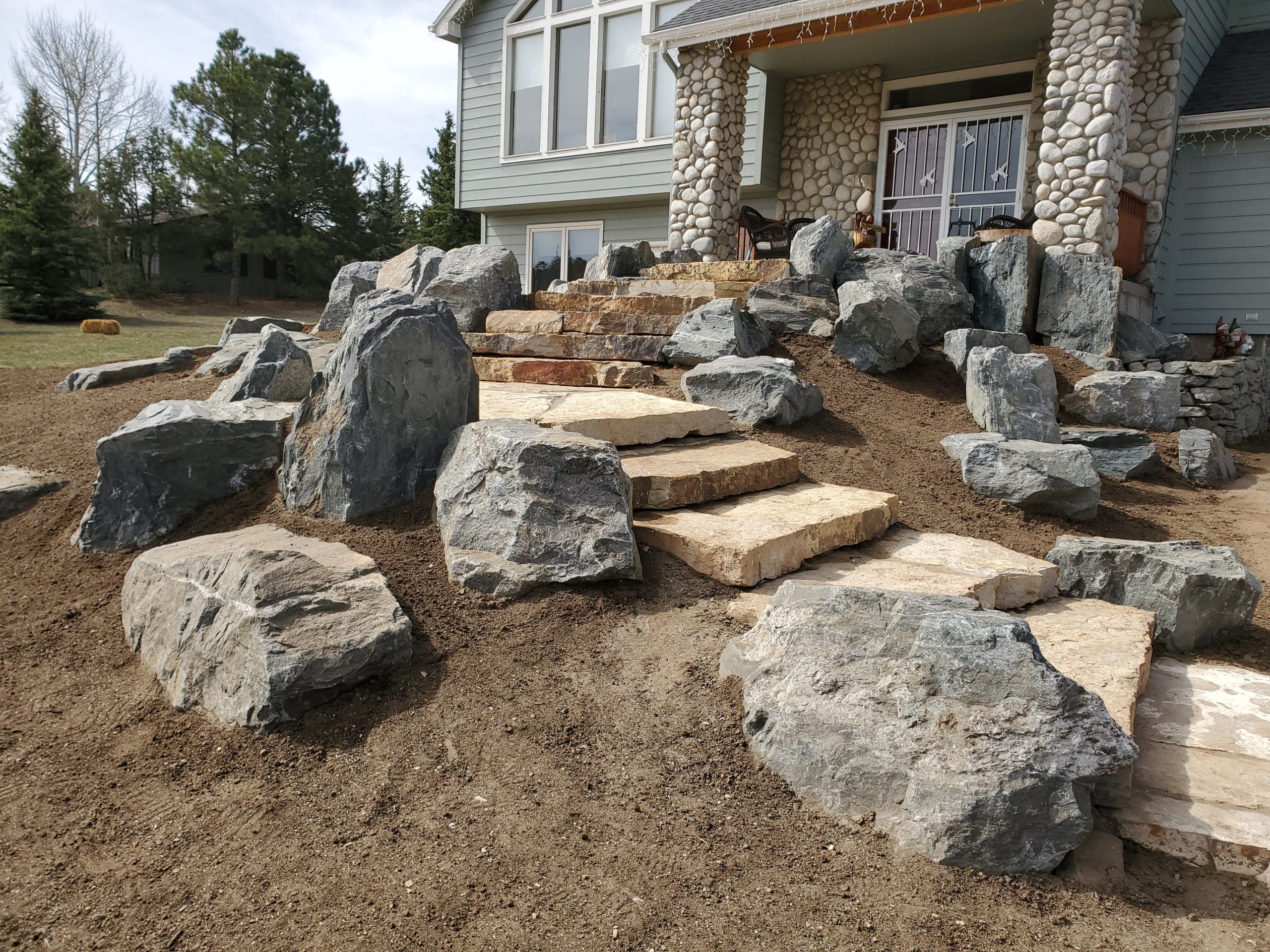 Large stones placed on either side of stepped path leading to front door.