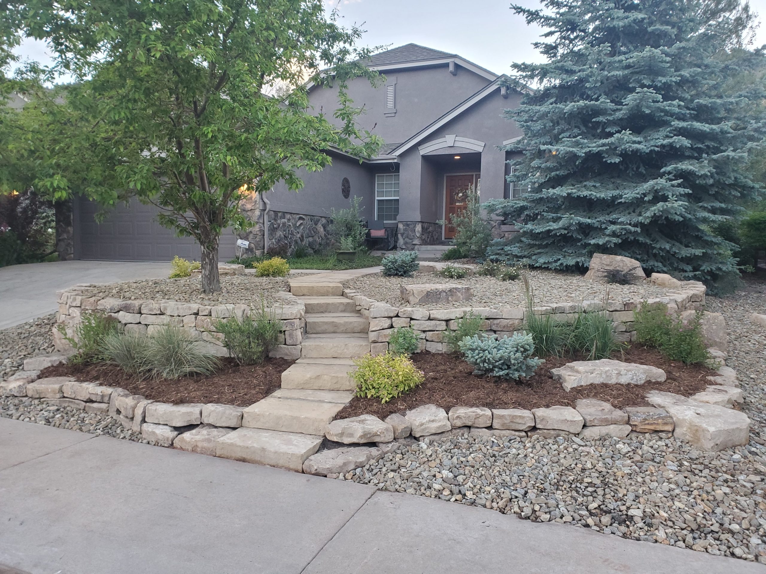 Finished front of house with steps, landscapping, and small retaining walls