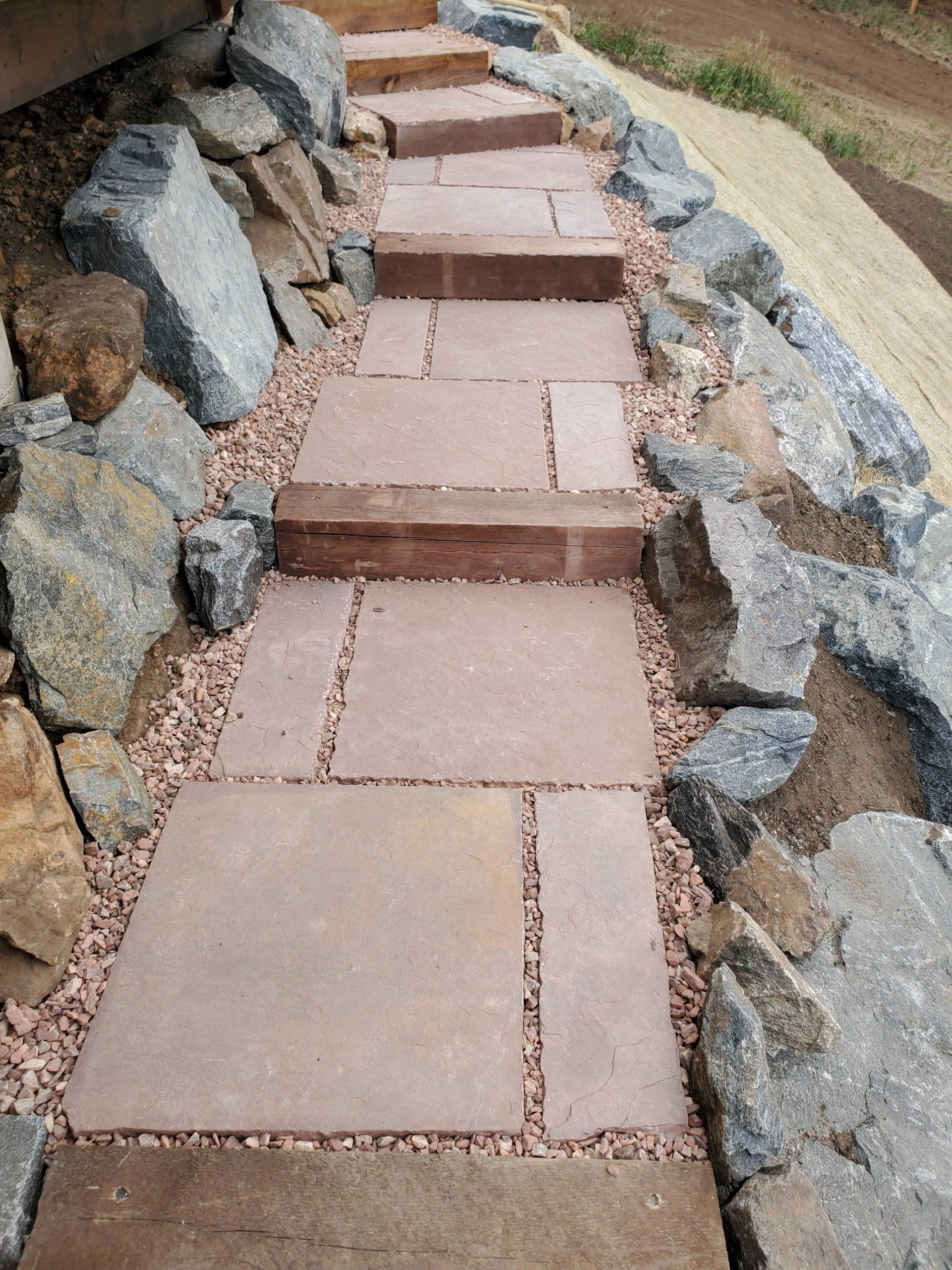 Oversized stairs made of red stone, with red gravel surrounding.