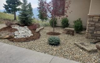 Completed entryway to house with small trees and gravel landscaping