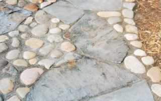 Large flat flagstone path with round river rocks interspersed.