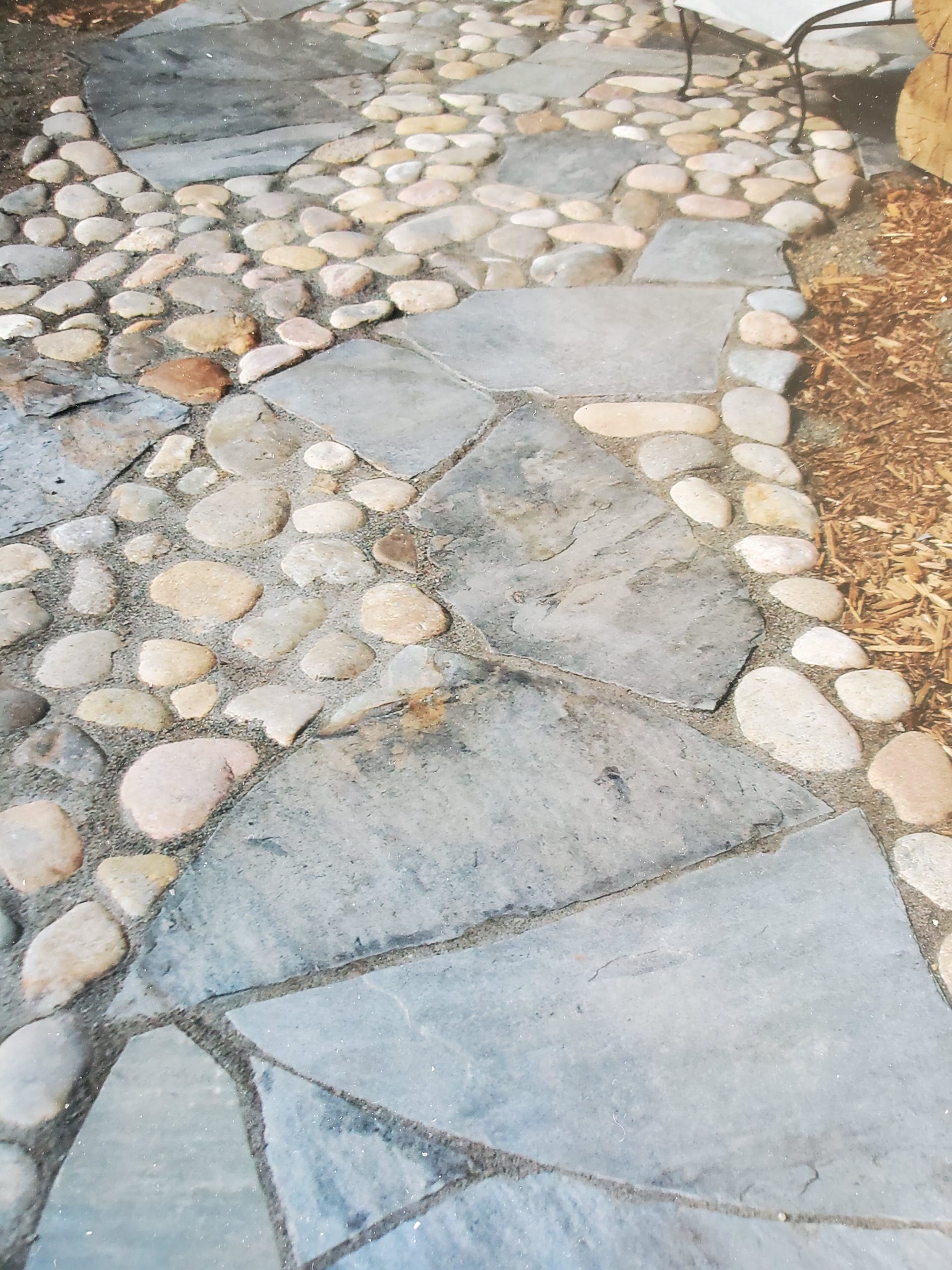 Large flat flagstone path with round river rocks interspersed.