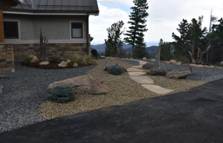 Xeriscaped front yard. Two tones of small stone with flagstone path between them