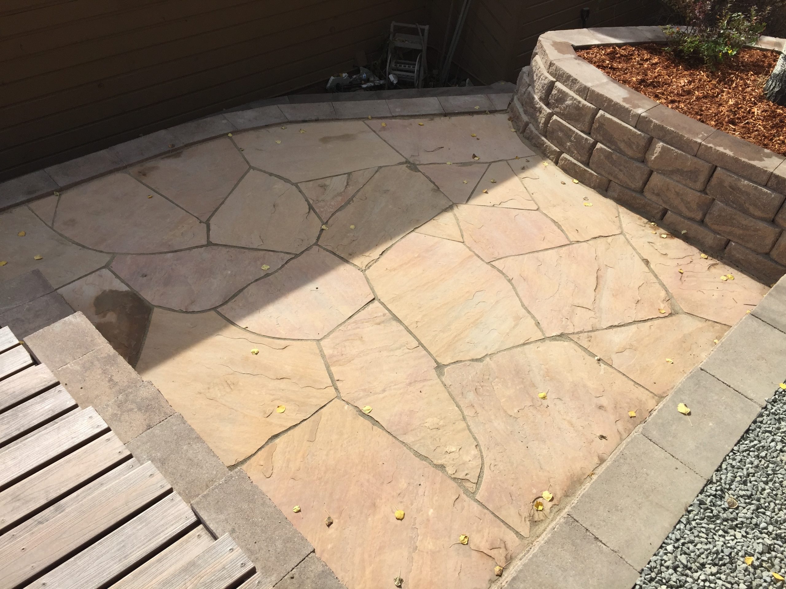 Small tan flagstone patio with landscape bed