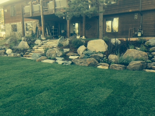 Large boulders strewn throughout landscaped backyard of house