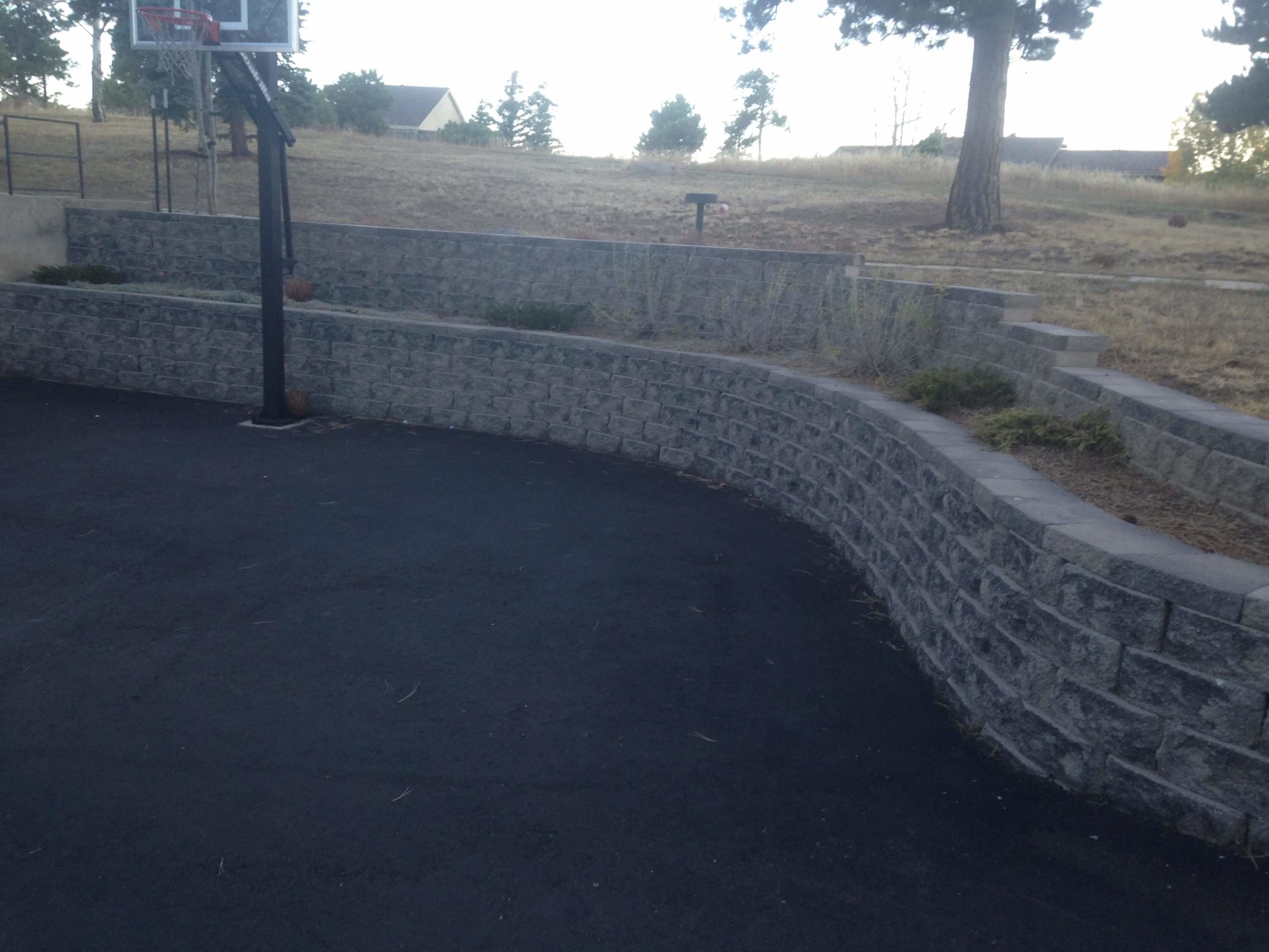 Double-terraced retaining wall next to paved basketball court