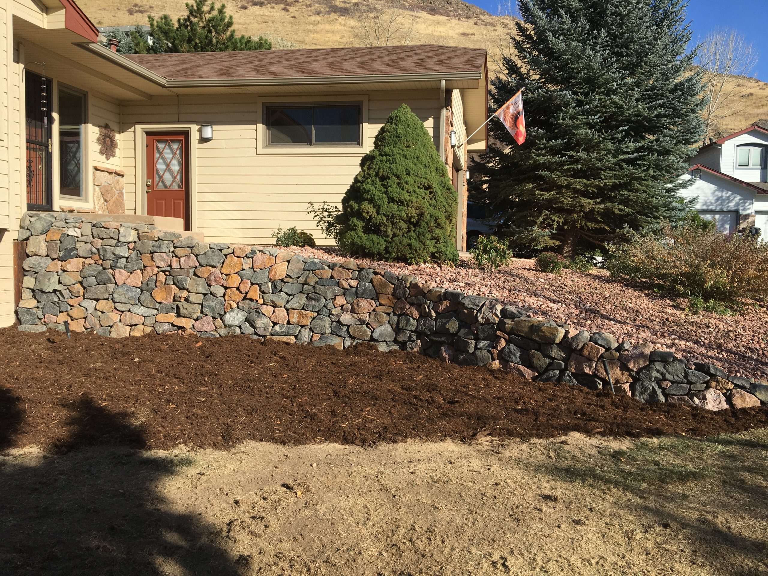 Natural rock retaining wall near entryway of house