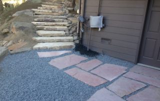 Red flagstone path leading to staircase around house to the upper level