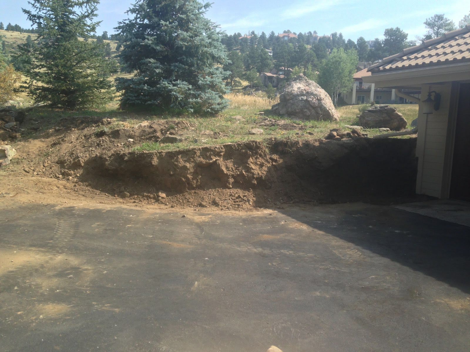 Old retaining wall removed, showing bare dirt next to garage
