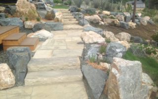 Stone pathway and stairs in backyard, with stone and plant landscaping