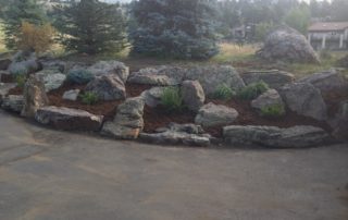 Large stone landscaping next to driveway, with bushes