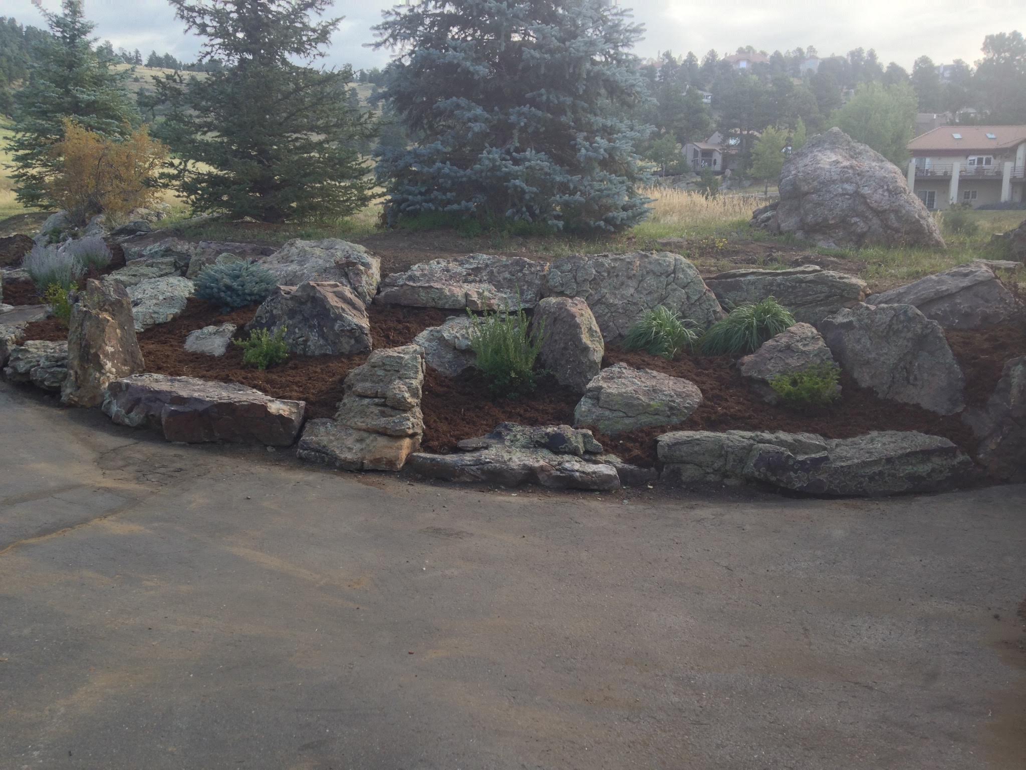 Large stone landscaping next to driveway, with bushes