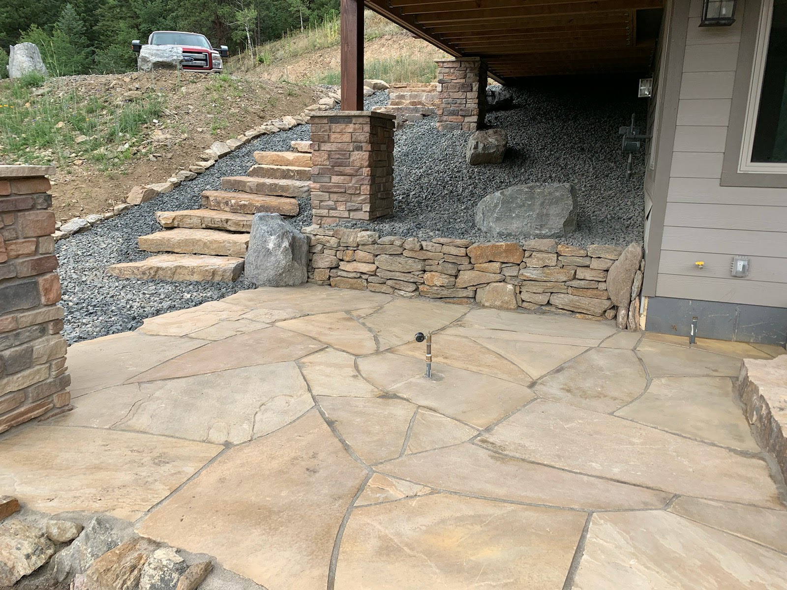 Covered flagstone patio with stone staircase alongside house