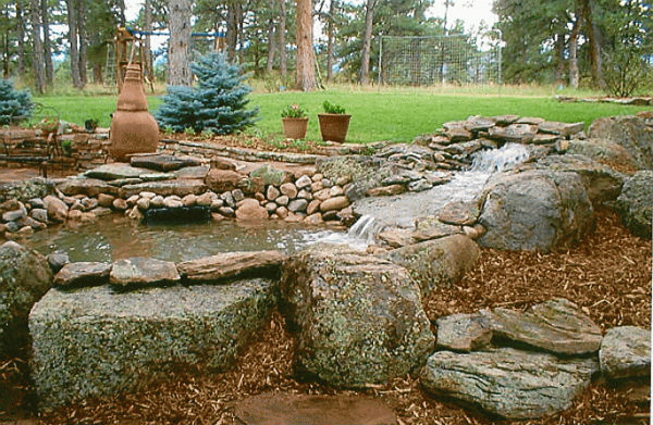 Multi-tier waterfall leading to pond. Rocks throughout