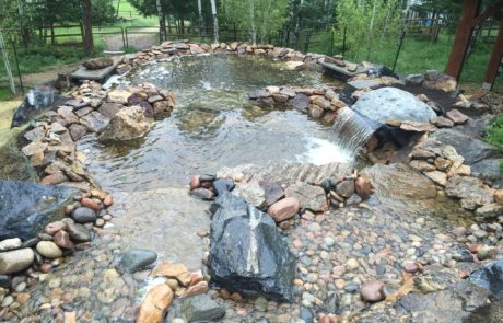 Water feature with waterfall. Large rocks and river rock throughout